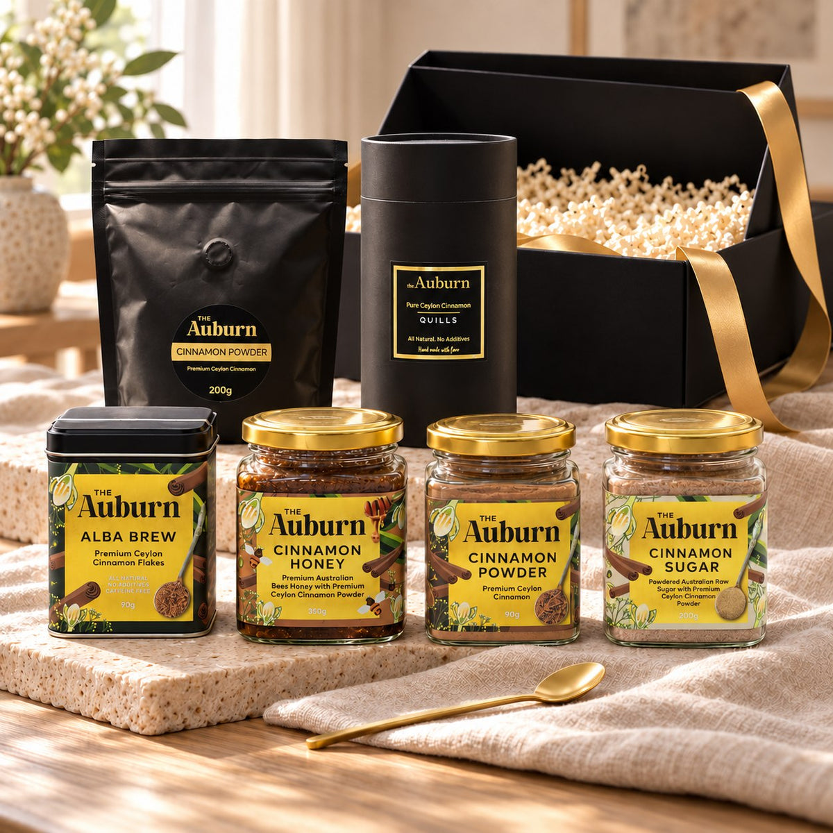 The Full Pantry hamper: cinnamon quills, jars of cinnamon powder, sugar and honey, a powder refill pouch, an Alba Brew tin and a gold tea spoon.