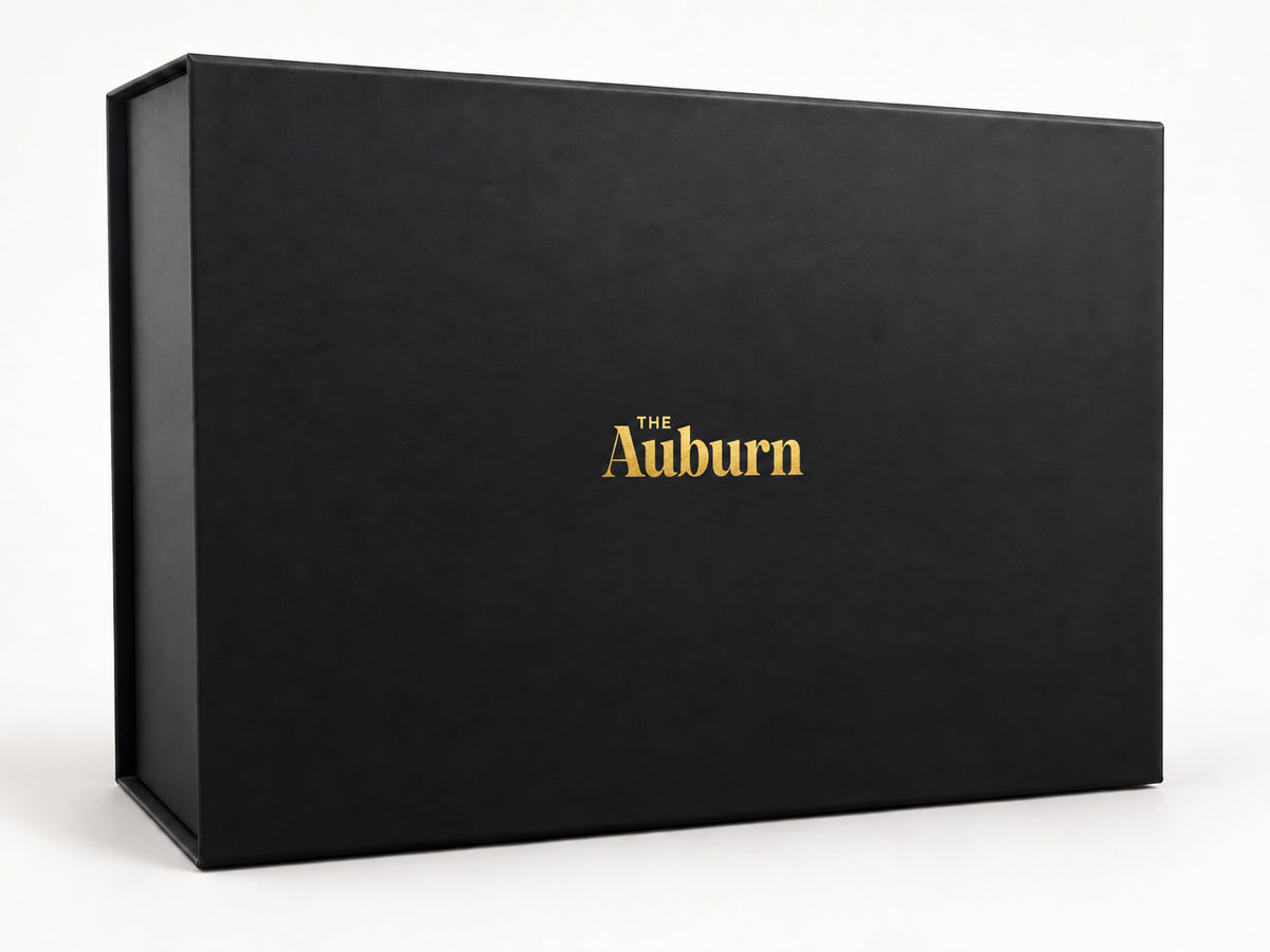 An open Auburn gift box being filled with hand-picked products, showing the build-your-own experience.